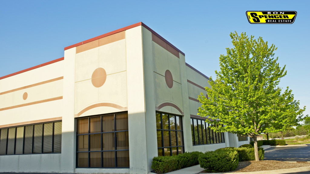 Light beige commerical corner building in a commercial plaza  with green leaf trees and brown trim, glass entrance doors and black trim. Commercial real estate in Ohio.