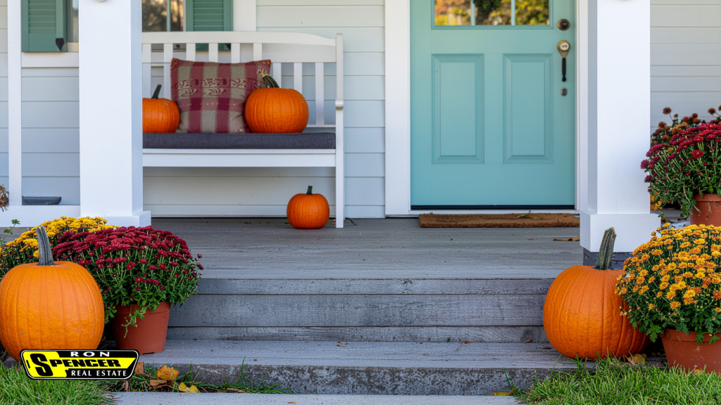 Front porch with white fence and pillars, white bench with orange pumpkins placed around, purple and yellow mums in pots and an aqua front door