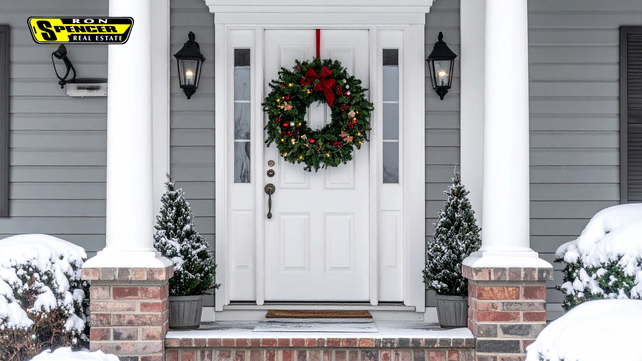 gray house front porch facade with white door and white pillars with green wreath on the front door