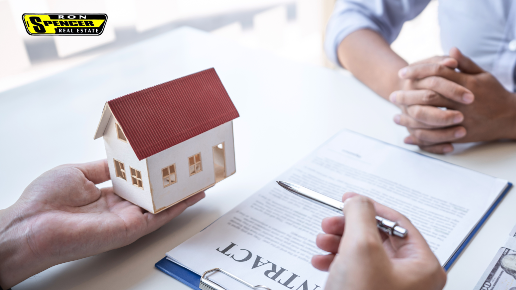 a desk with a home contract and a person holding a pen